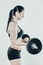 Sportive athletic woman lifting heavy barbells in light spacious