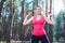 Sportive attractive girl working out with dumbbells, training in the forest. Fitness, sport, lifestyle concept