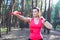 Sportive attractive girl working out with dumbbells, training in the forest. Fitness, sport, lifestyle concept