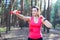 Sportive attractive girl working out with dumbbells, training in the forest. Fitness, sport, lifestyle concept