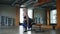 Sportive, blonde woman exercising in fitness club doing one leg sit ups while holding blue coloured dumbbells. Side view