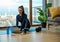 Sportive brunette types on laptop on blue mat near window