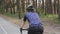 Sportive cyclist woman riding a bicycle in the park. Back side follow shot. Cycling concept. Slow motion