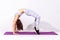 Sportive fitness woman in white top and tights practicing yoga, stretching in wheel exercise, urdhva dhanurasana pose, working out