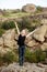 Sportive girl smiling, showing peace, standing on rock in canyon.