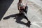 Sportive lady sits holding bottle of water on concrete ground on sunny day