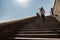 Sportive lady in tracksuit runs up old stone steps under clear sky