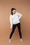 Sportive and playful girl in white pullover and black leggings grimace in studio