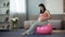 Sportive pregnant lady sitting on fitness ball, listening to her babys beating