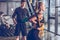 Sportive woman exercising with trx gym equipment with trainer near by