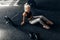 Sportive woman, in sportswear, sits on the floor at the gym, after a successful workout at the gym