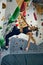 Sportive young girl in sportswear training, practicing bouldering activity, climbing artificial rock, wall indoor