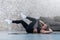 Sportive young lady doing crisscross crunch exercise lying on a rug at modern studio