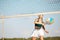 Sportive young woman playing beach, paddle tennis, hitting ball with racket. Outdoor training on warm summer day