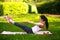 Sportive young woman stretching, doing fitness exercises in park