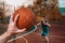 Sports and basketball. A man`s hand holds a basketball for submission. In the background, a teenager in a blur preparing to catch