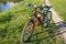 A sports bicycle on a green grass near a city lake