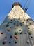 Sports climbing wall in perspective with various hooks, hanging rope belay. View from below