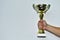 Sports cup in a man`s hand on a white background. Champion golden trophy cup. Cup sport after a winning. Gold championship winner