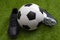 Sports equipment, athletics competition and sporting event concept with soccer ball, leather cleats or football boots on green