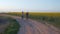 Sports family, young athletes man and girl with kanekalon braids run around on nature on blossom colza field against