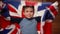 Sports fan concept. A little boy with a British flag on a wooden background. A seven-year-old kid shakes the flag of