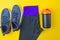 Sports flat layout. Fitness accessories sneakers, clothes, bottle on a yellow background. Doing fitness at home