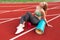 Sports girl sits on the stadium runway.