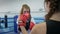 Sports hobby, young woman holds boxing paws for girl who beats on ring in gym
