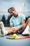 Sports injury. Young tennis player touching his knee while sitting on the tennis court