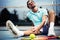 Sports injury. Young tennis player touching his knee while sitting on the tennis court