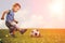 Sports kid. Boy playing football. Baby with ball on sports field