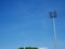 Sports light pole or Stadium Light tower in sport arena on blue sky with clouds.