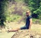 Sports man with a beard and a good haircut in sunglasses and shorts, smiling, sitting on the bank of a mountain river on natural g