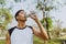 Sports man drinking water after exercising on background of green trees