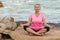 Sports mature woman at the beach make meditate exercises