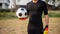 Sports and recreation concept a male teenage goalkeeper wearing black outfit and a pair of colorful gloves holding a soccer