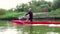 Sports rowing on the kayak. The man floats down the river along the wood.