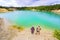 Sports tourists men and women stand on the shore of a picturesque azure lake at the site of a quarry