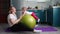 Sports training at home. A young mother does exercises with a fitball and rolls her child on the ball. The concept of sports train