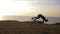 Sports training in nature, athlete guy doing flips trick on river coast against sky in afterglow