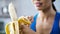 Sports woman peeling sweet banana for snack, hungry after active workout in gym