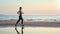 Sports woman running outdoor training at sunset beach sea landscape enjoy healthy lifestyle slowmo