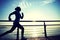 Sports woman running on wooden boardwalk sunrise seaside