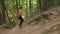 A Sports Young Woman Running Down the Hill Crest In The Wood By The Trail