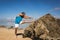 sportsman with armband stretching leg near rock