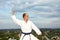 Sportsman with blue belt doing formal karate exercises on city background