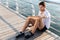 Sportsman with bottle of water sitting and relaxing on pier