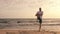 Sportsman exercising and stretching his legs on beach at sunset