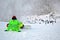 sportsman in green suite with skateboard seating on white snow and look ahead, winter sport entertainment,